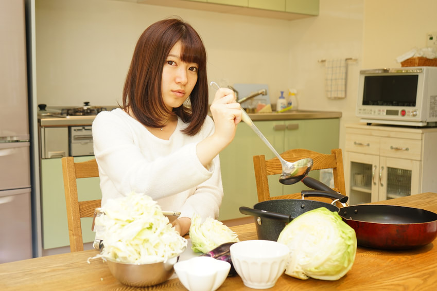 Young woman using a smartphone while cooking